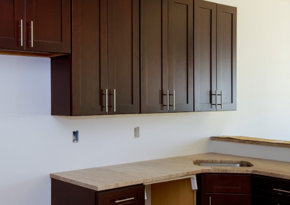 Cocina a medida con muebles altos en madera oscura y encimera de piedra natural