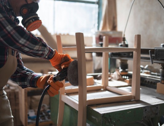 Lijado de la estructura de un mueble de madera con lijadora orbital durante su restauración