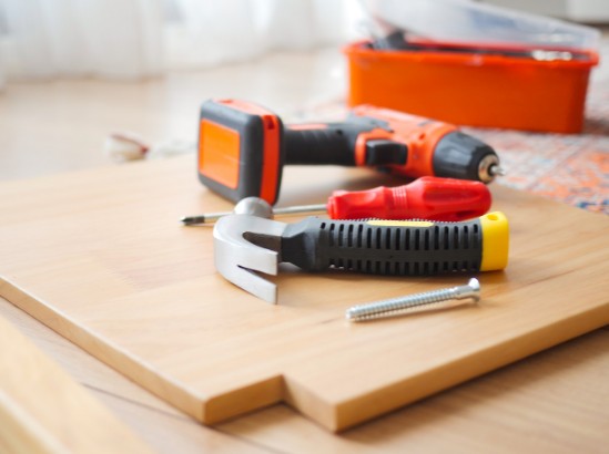 Tablero de madera y herramienta de montaje preparados en obra para instalar el mobiliario