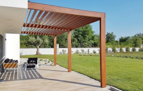 Pérgola adosada a la fachada con techo de lamas de madera sobre una tarima de exterior