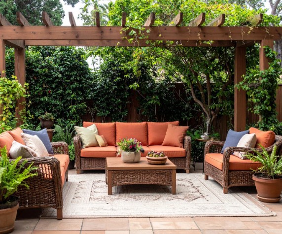 Pérgola de madera rústica sobre un patio mediterráneo con muebles de exterior