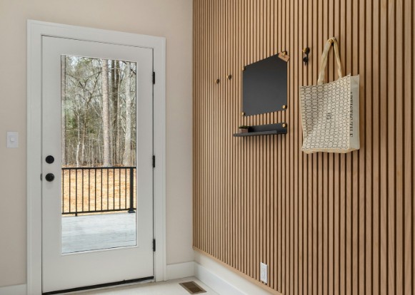 Recibidor forrado con panel de lamas de madera de suelo a techo junto a la puerta de entrada