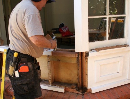 Carpintero reparando el durmiente inferior de una ventana de madera con carcoma en Málaga